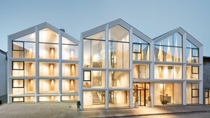 Un hotel moderno con fachada de vidrio, varios pisos y una escalera que conduce a los niveles superiores.