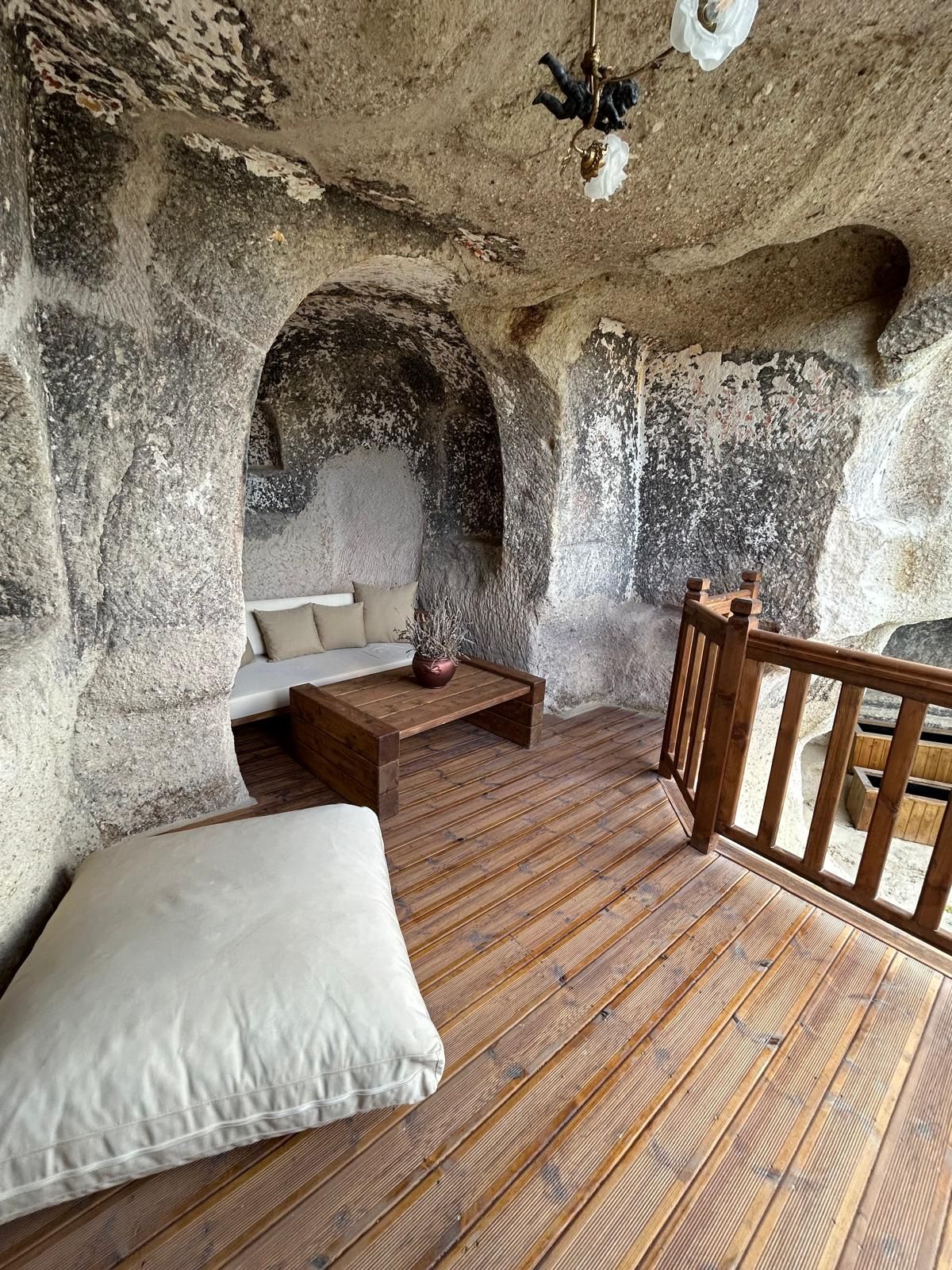 A rustic interior with a wooden floor, a sofa, a white pillow, and a wooden railing.