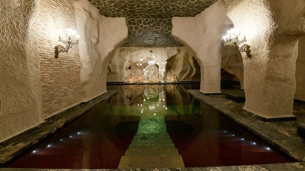 A stone-walled pool with a reflective surface, surrounded by walls with embedded lighting fixtures. - Sacred Mansion (Nevsehir)