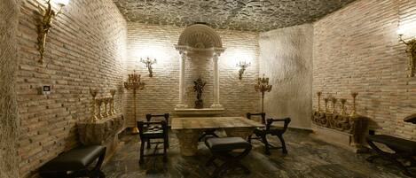 A room with a stone brick wall, a marble floor, and a central altar with candles.