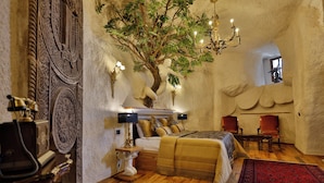 A bedroom with a large bed, a chandelier, and a tree sculpture. - Sacred Mansion (Nevsehir)