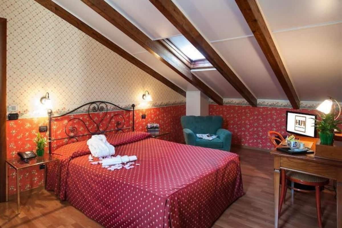 A bedroom with a bed, a desk, a chair, and a skylight.