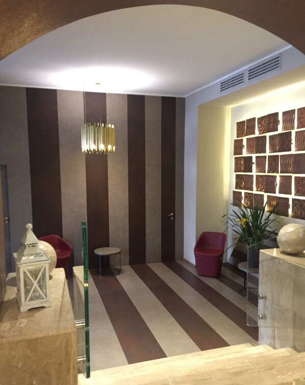 Un interior moderno con piso a rayas, lámpara colgante, una silla roja y una pared con paneles decorativos.