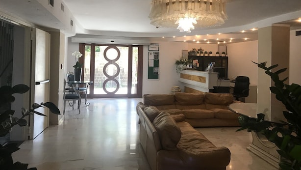 Un'ampia zona giorno con un divano in pelle, un lampadario e una reception.