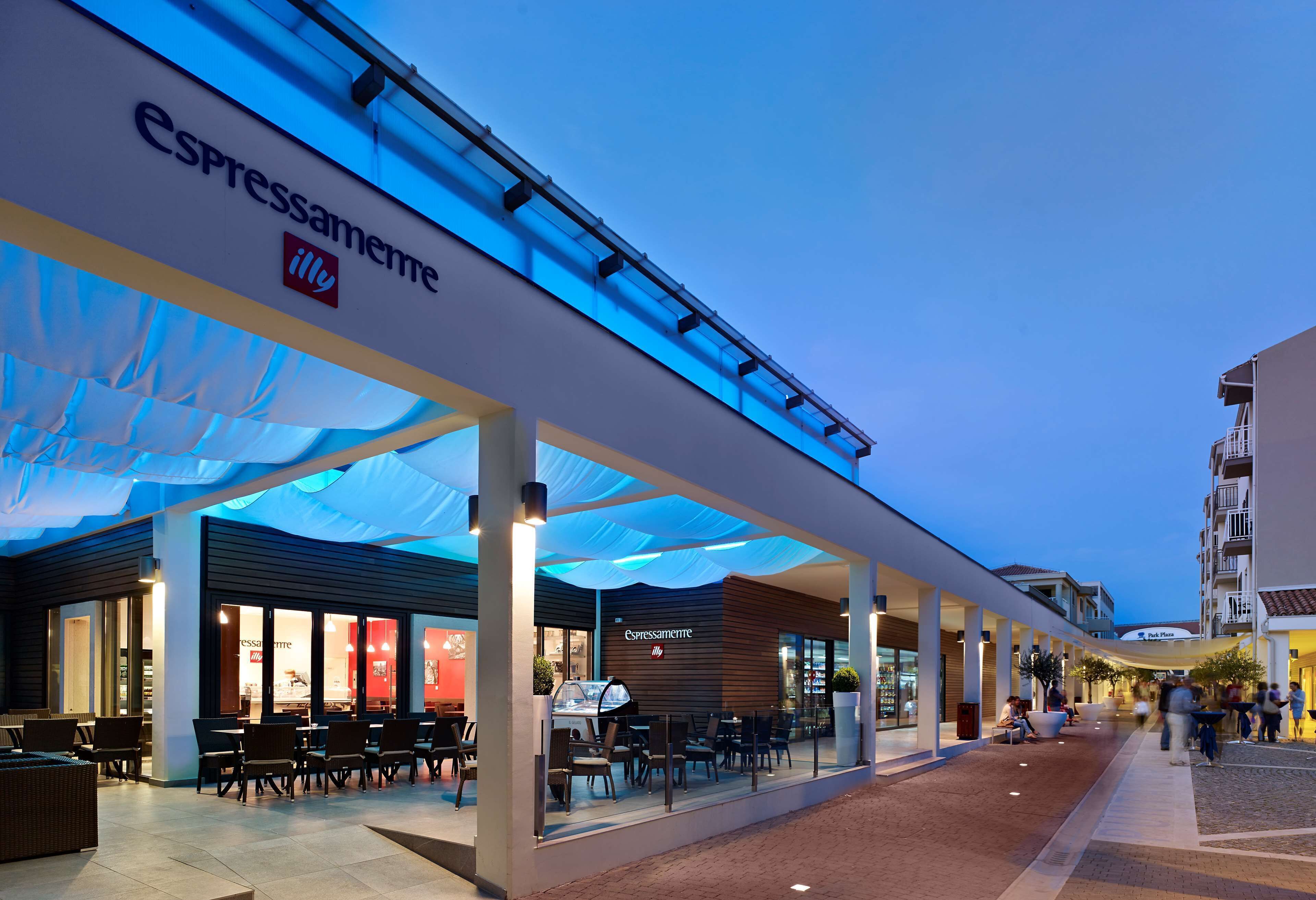 A modern outdoor café area with seating and a visible restaurant named 'Espressamente'.