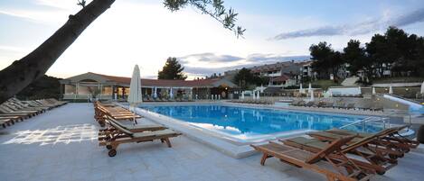 A pool area with sun loungers and a clear blue pool.