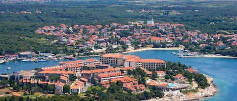 Un pueblo costero con edificios de techo rojo, un puerto deportivo y una playa.
