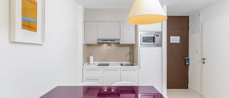 A modern kitchen with white cabinets, a stainless steel microwave, and a hanging light fixture.