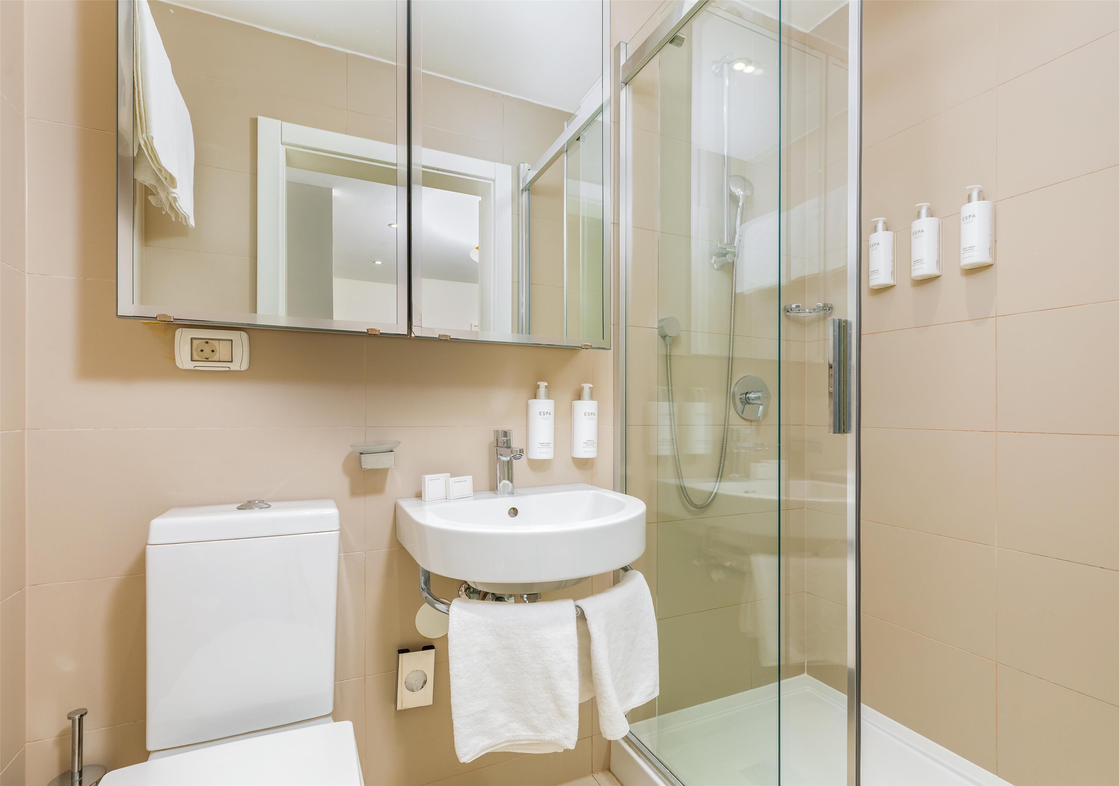Une salle de bain avec une douche à parois de verre, un lavabo blanc et des toilettes.