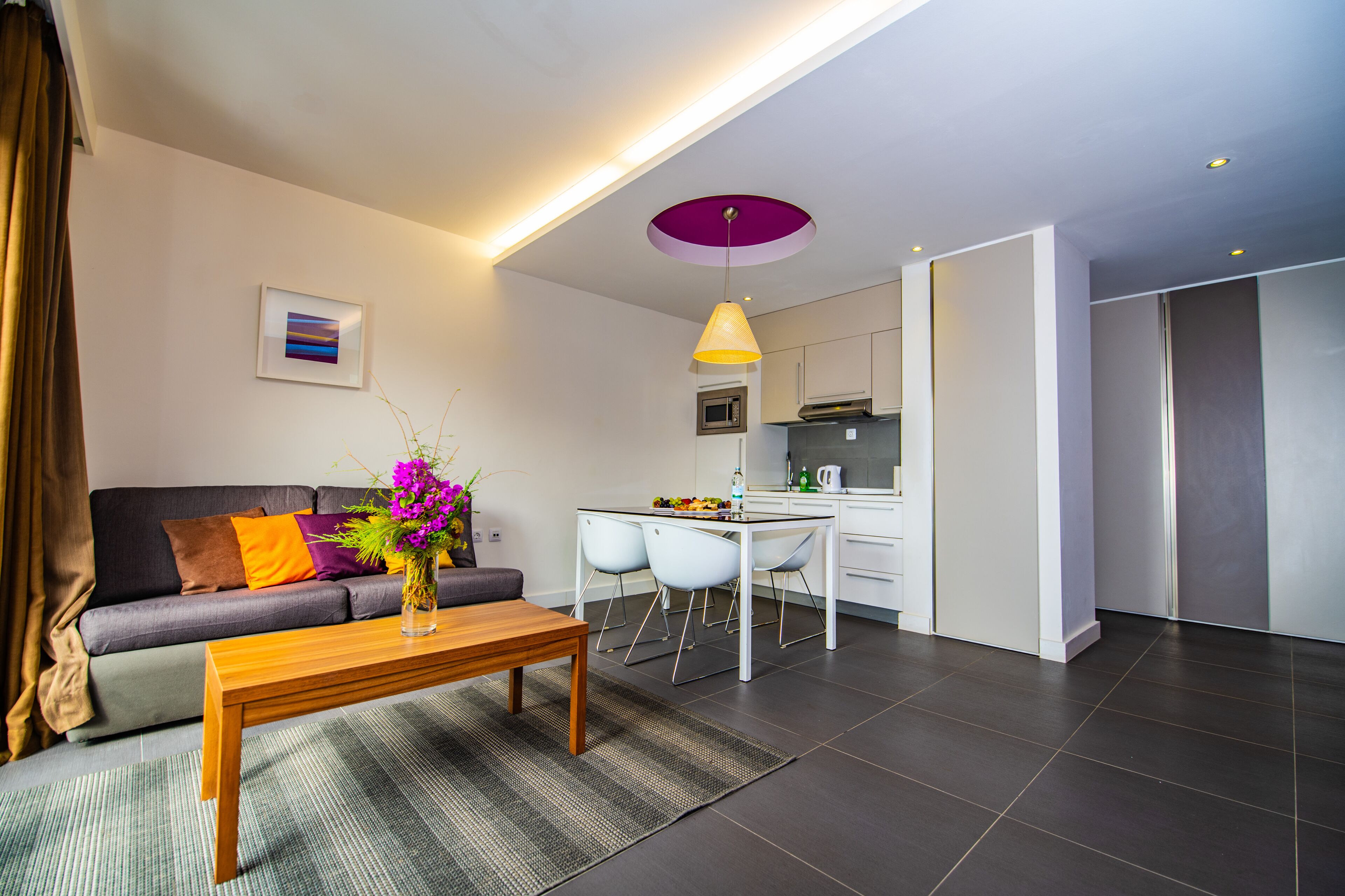 Una sala de estar moderna con un sofá, una mesa de centro y un comedor con sillas y una pequeña cocina.