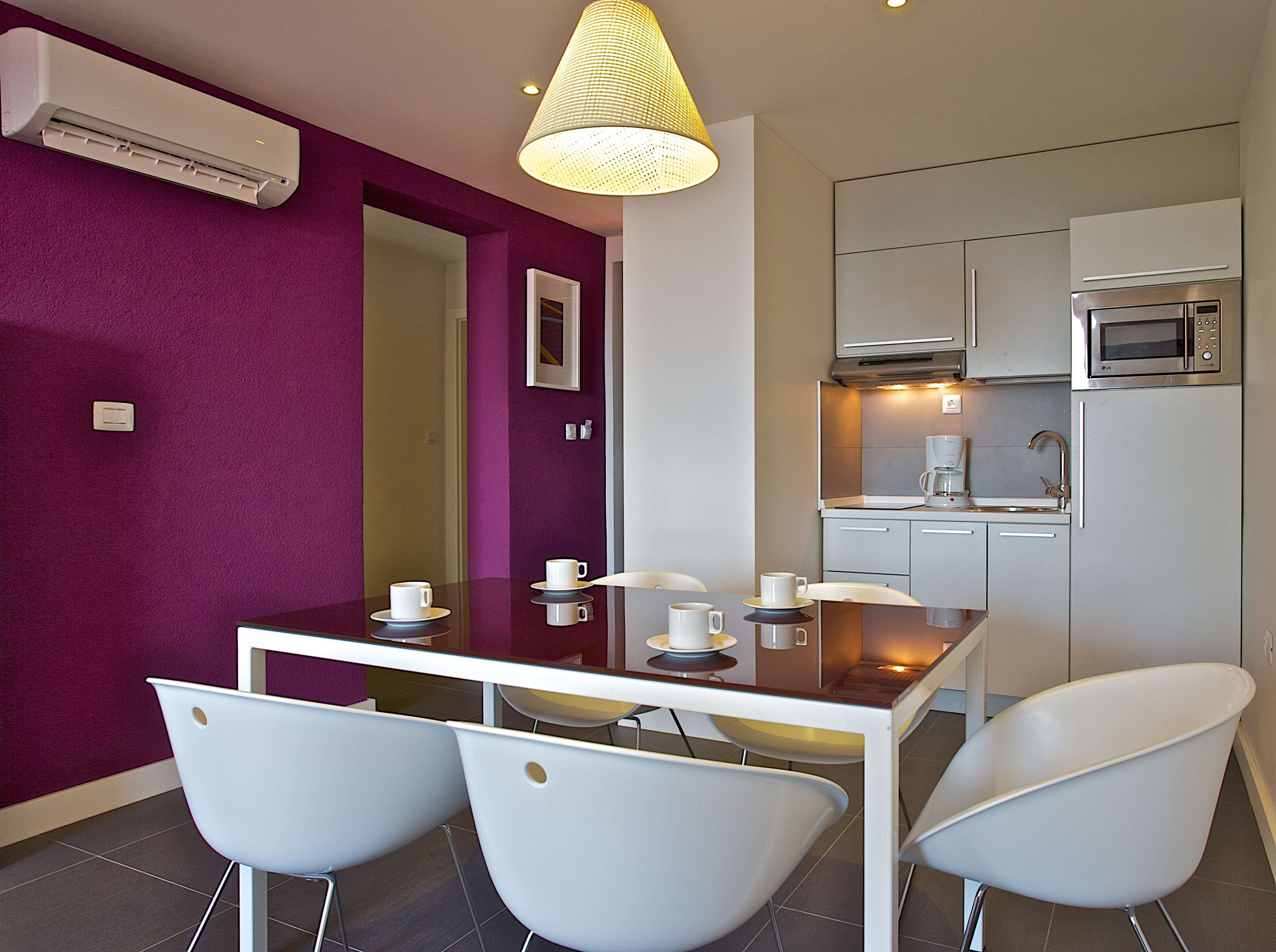 A compact kitchen with a microwave, coffee maker, and modern white cabinets.