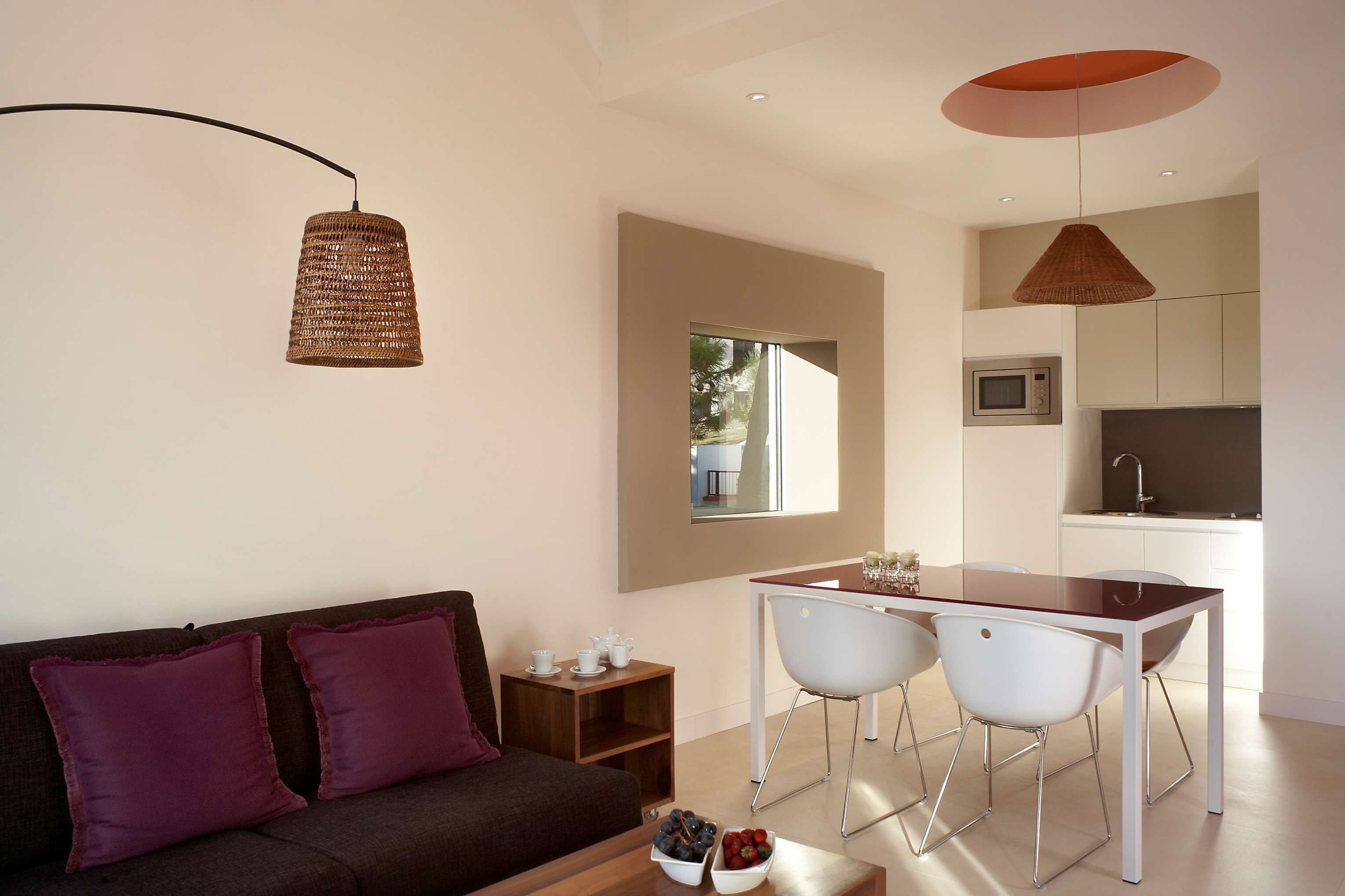 A modern living space with a sofa, dining table, chairs, and a kitchen area.