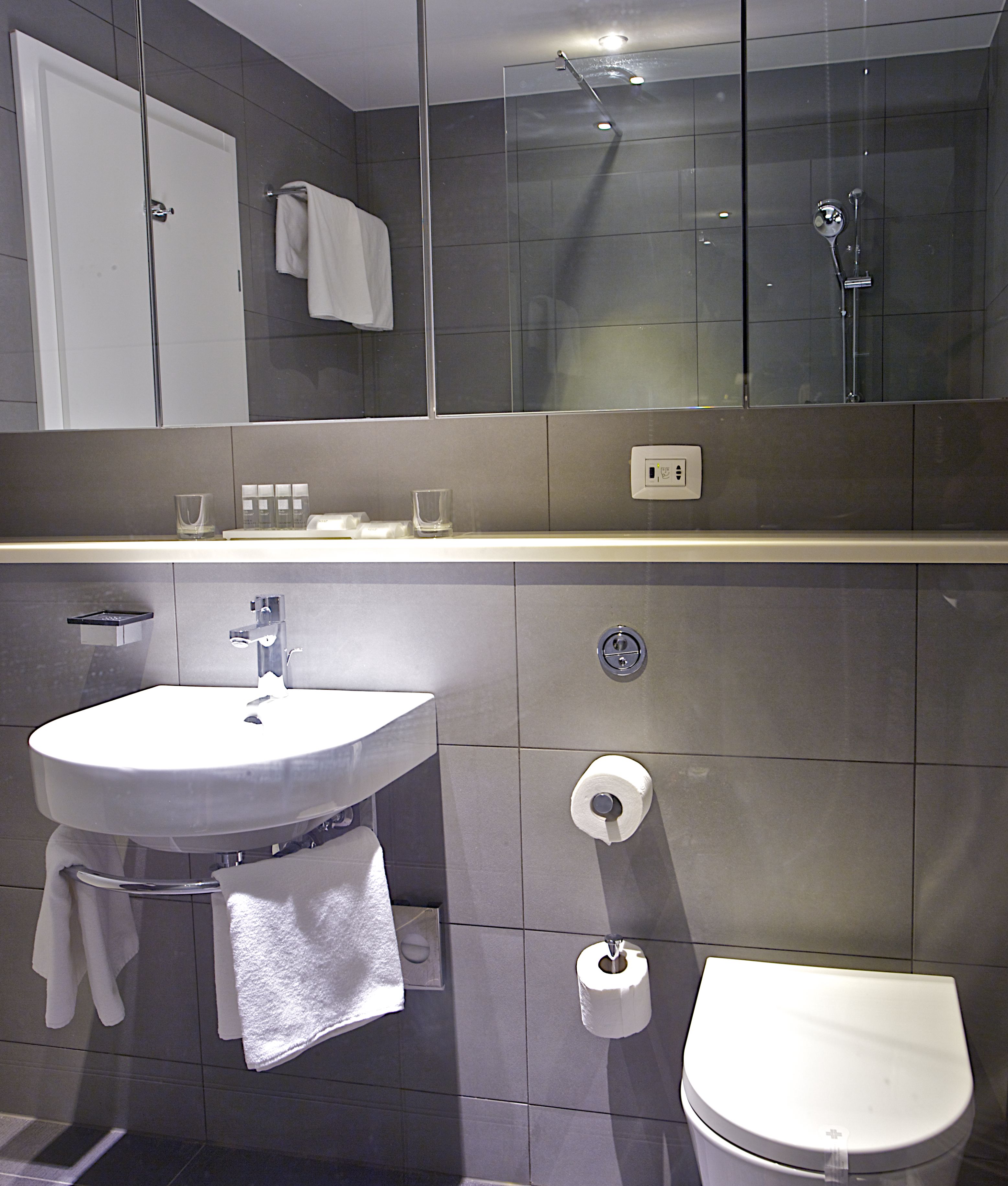 A modern bathroom with a sink, toilet, and glass shower enclosure.