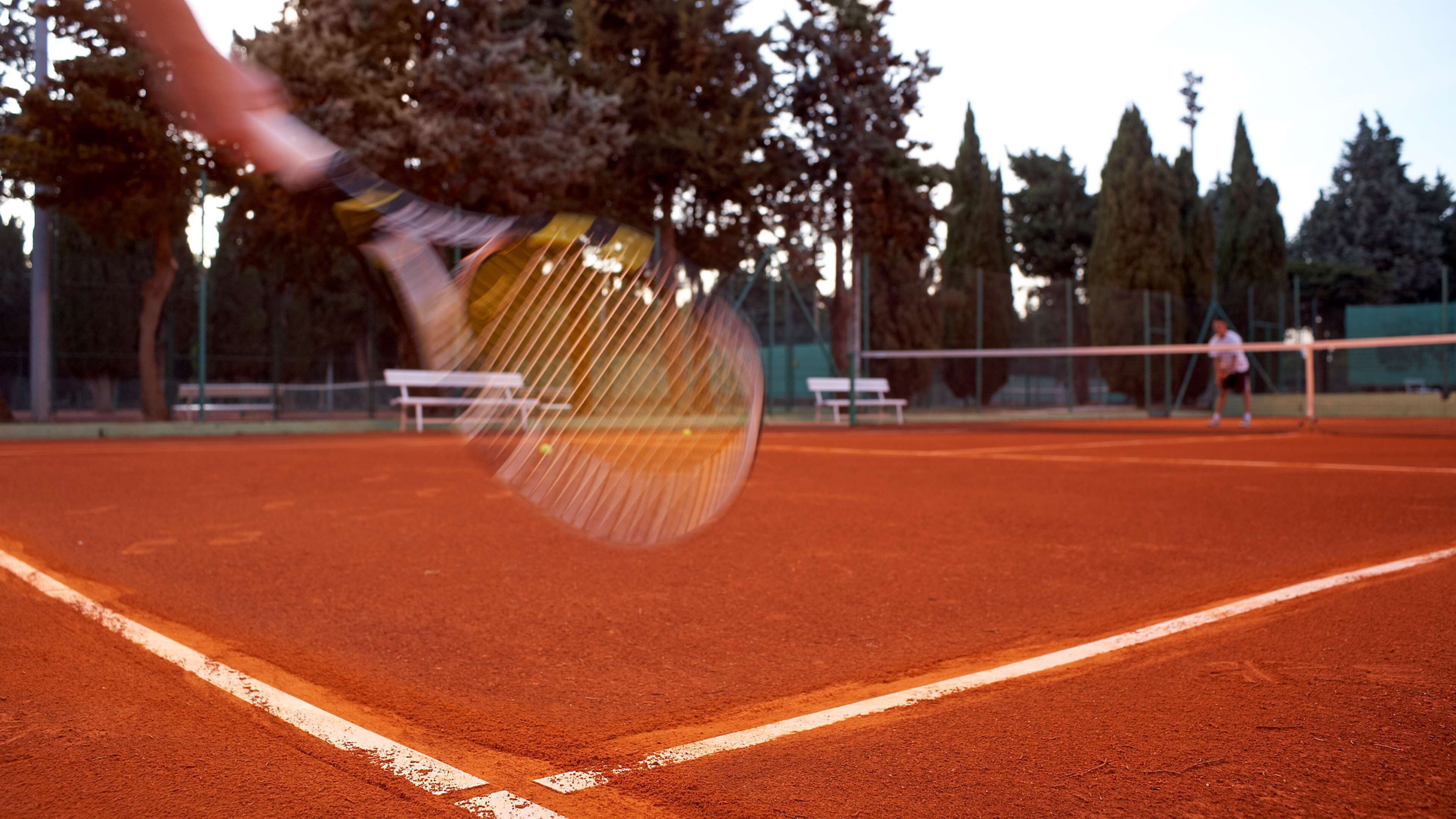 A tennis court with a net and a player in motion.