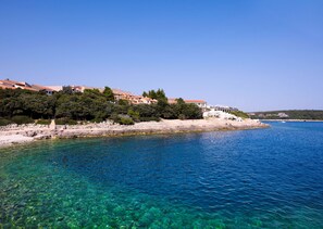 A coastal area with clear blue water, rocky beach, and buildings with red roofs. - Park Plaza Verudela Pula (Pula)