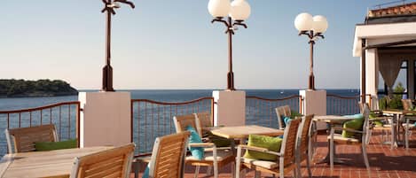 An outdoor seating area with tables and chairs, overlooking a body of water.