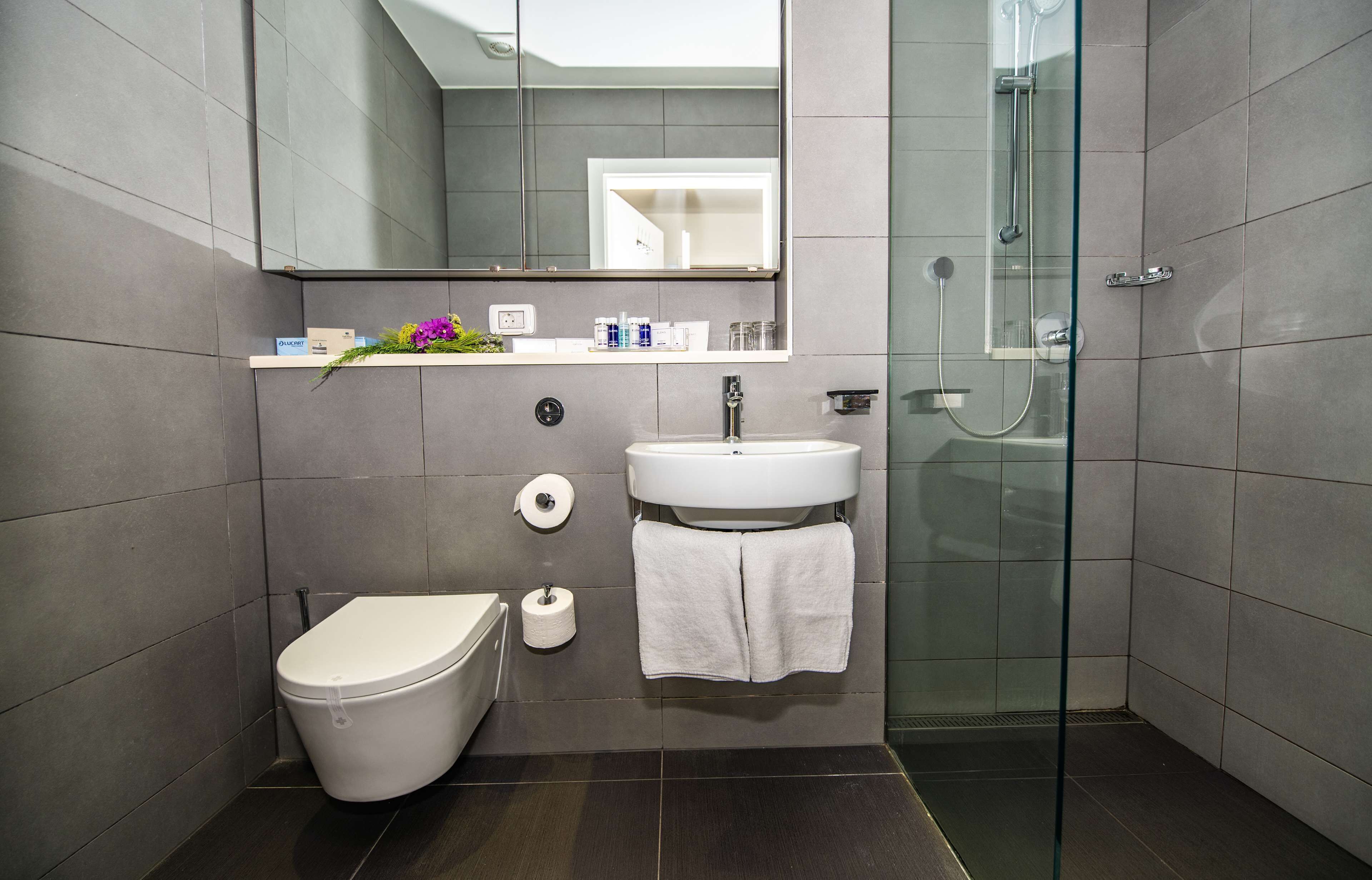 Een moderne badkamer met toilet, wastafel en douche.