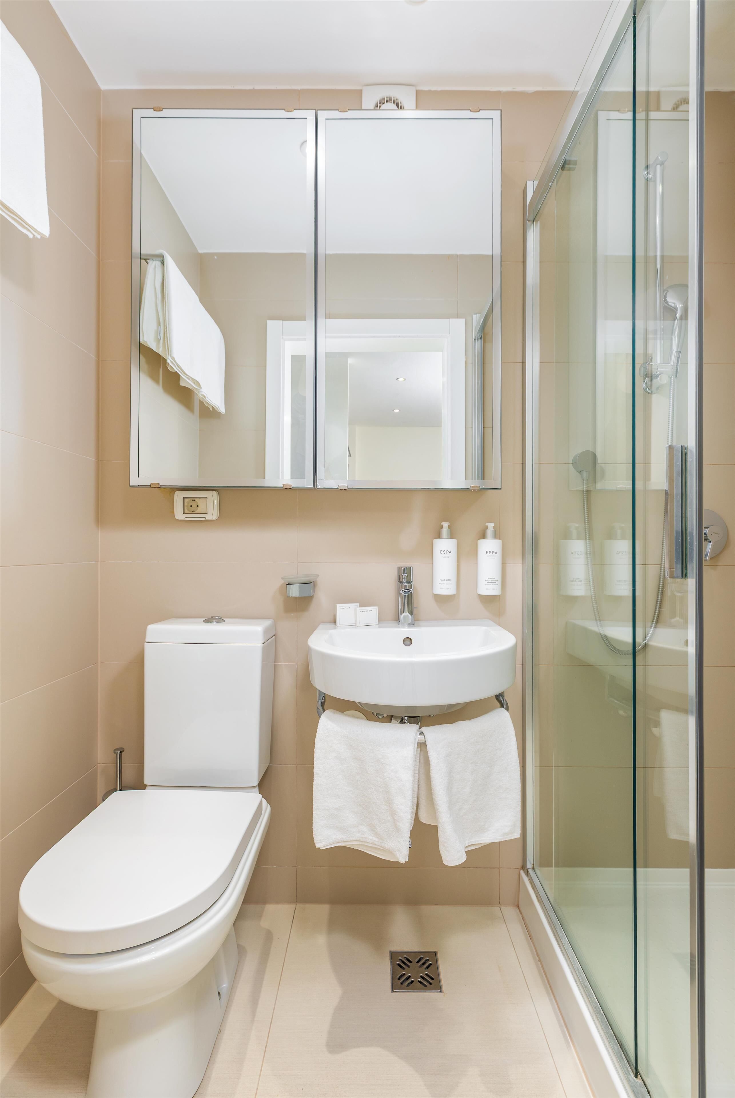 A modern bathroom with a toilet, sink, and glass shower enclosure.