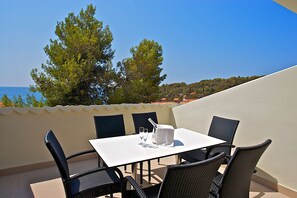 A terrace with a table and chairs, overlooking a coastal area with trees and a view of the sea. - Park Plaza Verudela Pula (Pula)