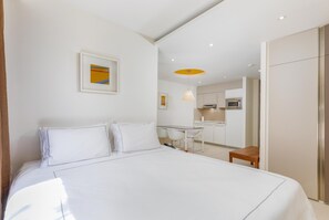 A hotel room with a bed, a desk, a chair, a small table, a microwave, and a kitchenette. - Park Plaza Verudela Pula (Pula)