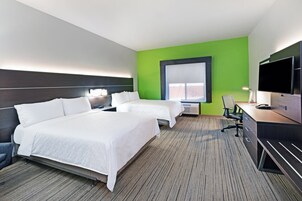 Una habitación de hotel con dos camas, un escritorio, una televisión y un ventanal grande.