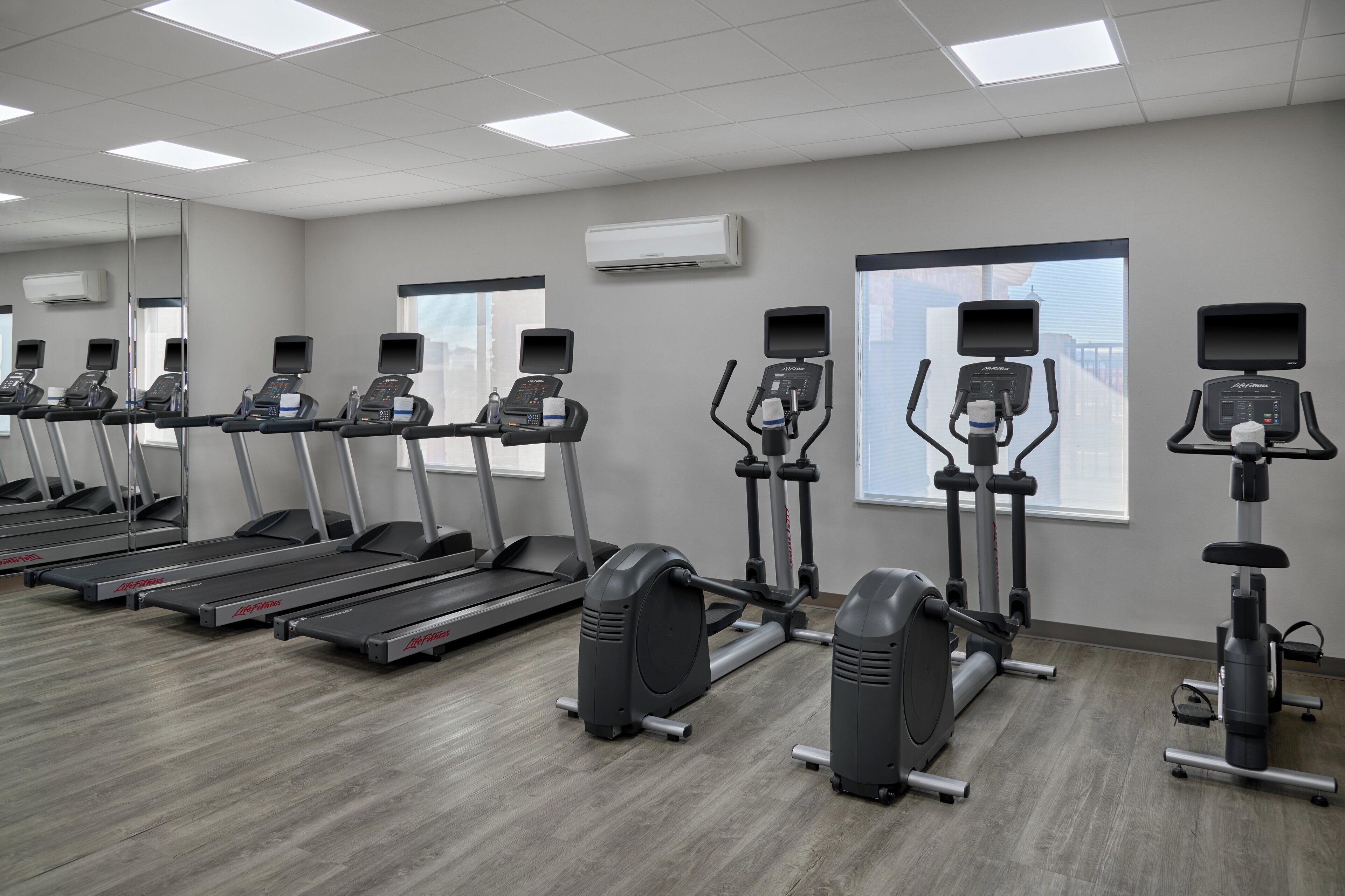 Un gimnasio con cintas de correr, máquinas elípticas y bicicletas estáticas dispuestas en filas.