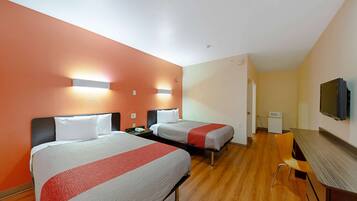 Quarto de hotel com duas camas, uma escrivaninha, uma cadeira e uma televisão.