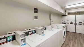 Uma lavanderia comercial com várias máquinas de lavar e secar, painéis de controle e sistemas de ventilação.