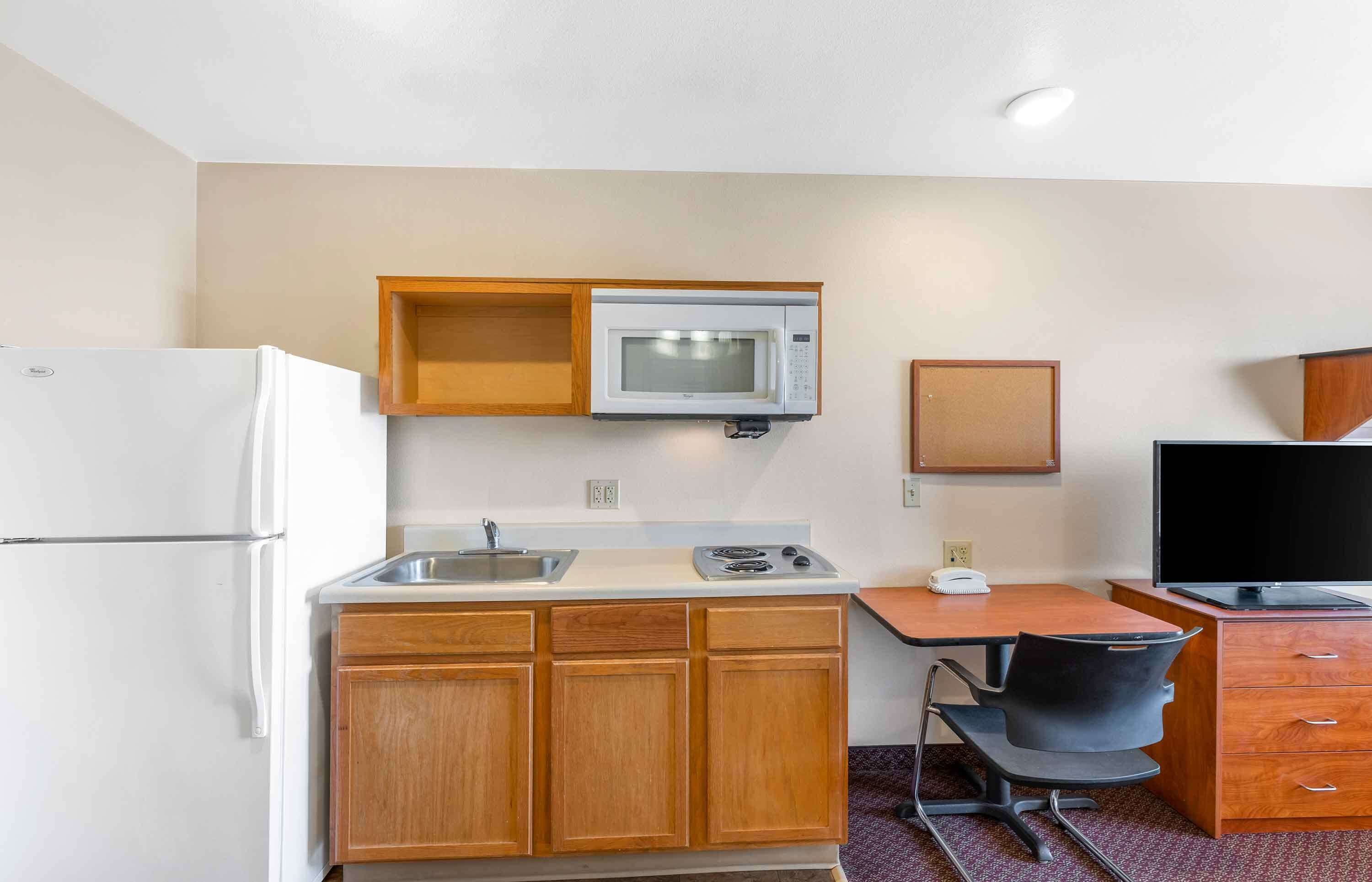A compact kitchen with a microwave, sink, stove, and wooden cabinets.