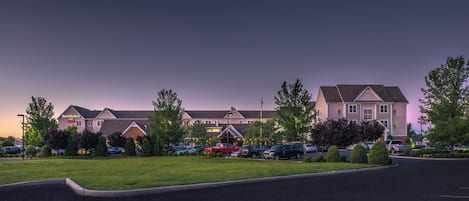 A residential building complex with multiple houses, a parking lot, and a grassy area.