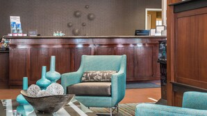 A reception area with a wooden reception desk, teal armchairs, and decorative vases. - Residence Inn Marriott Waynesboro (Waynesboro)