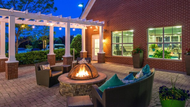 An outdoor patio with a fire pit, wicker furniture, and a brick building with large windows. - Residence Inn Marriott Waynesboro (Waynesboro)