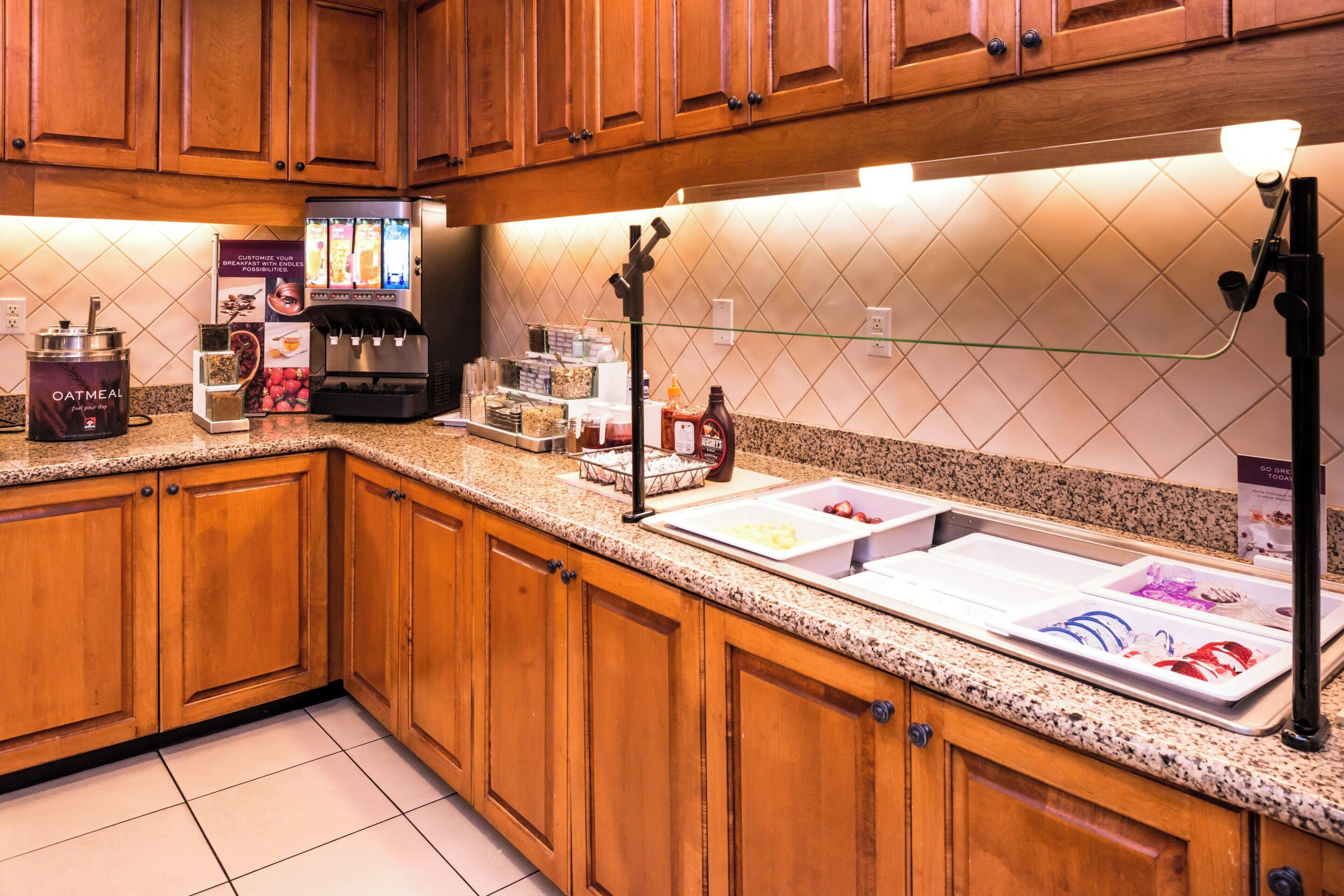 A kitchen with wooden cabinets, a coffee machine, a glass display case, and a sign advertising oatmeal.