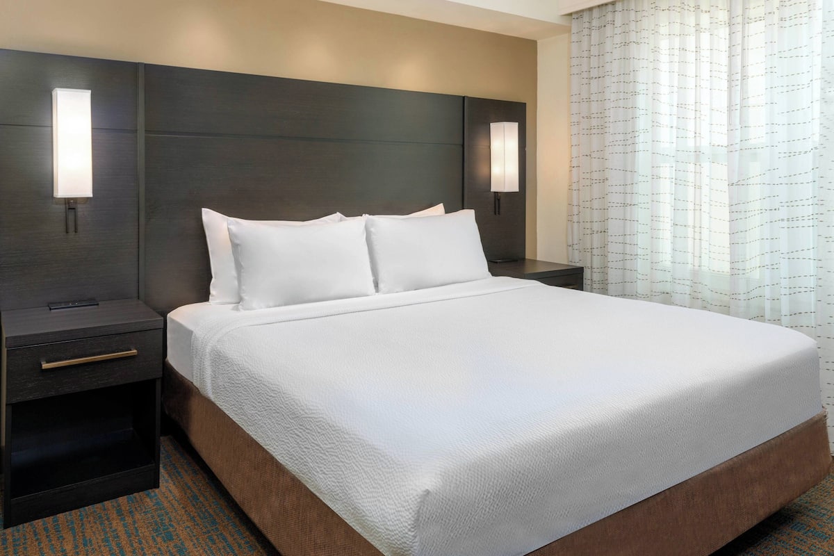 A hotel room with a large bed, two bedside tables, and a headboard.