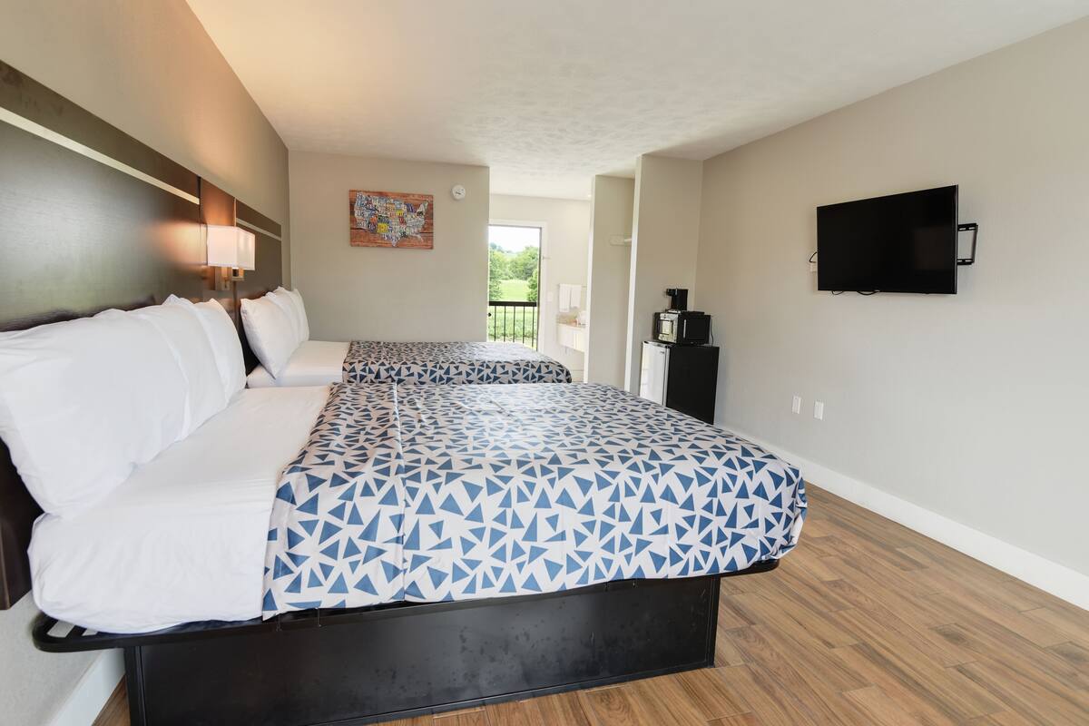 A hotel room with a bed, a TV, a coffee machine, and a balcony view.