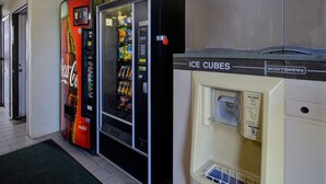 Máquina expendedora con el logotipo de Coca-Cola, un botón pulsador y una exhibición de aperitivos.