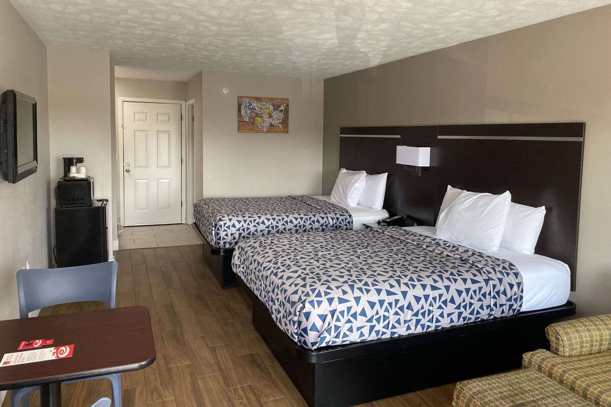 A hotel room with two beds, a desk, and a chair.