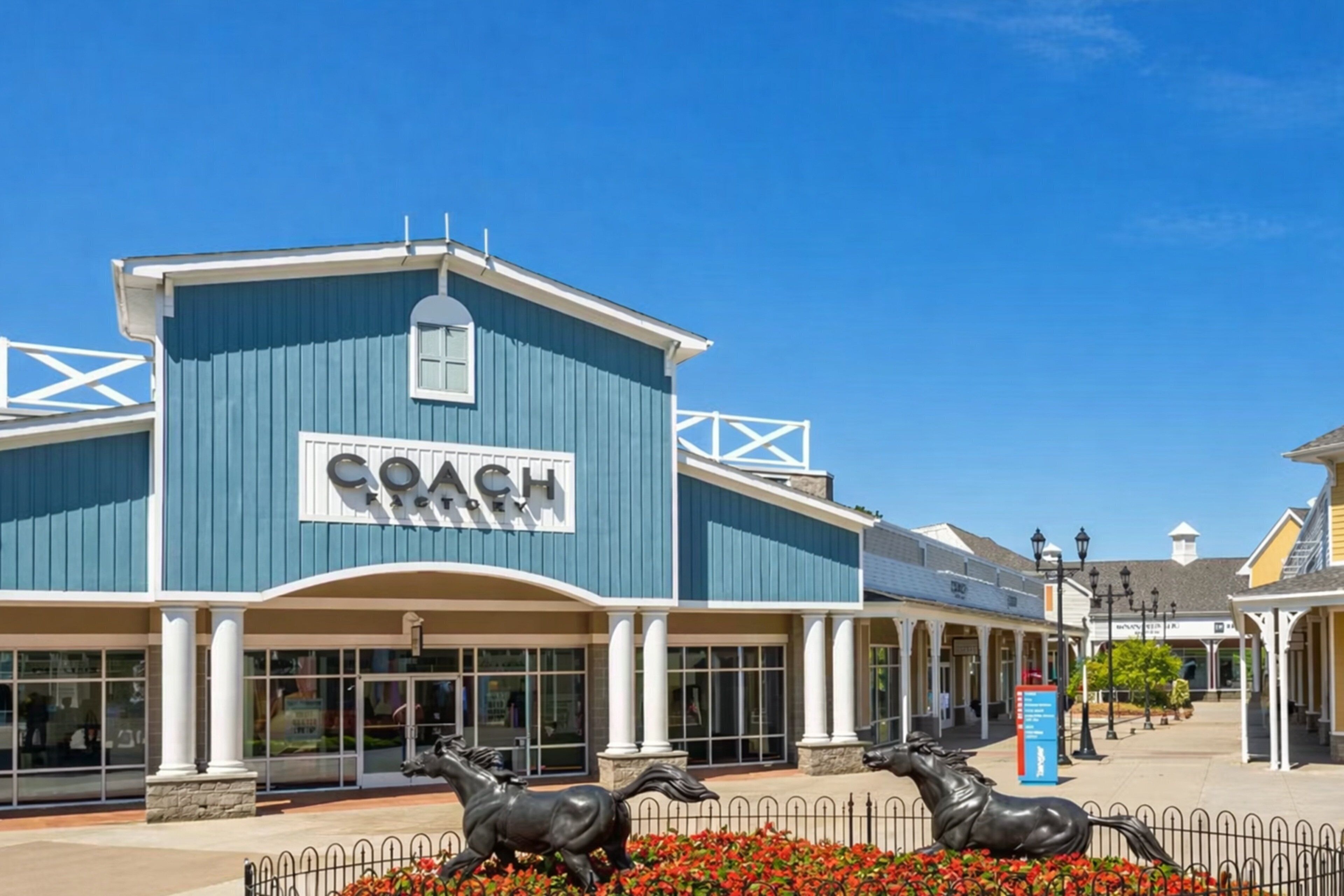 A building with a 'COACH' sign, a covered entrance, and a decorative horse statue.