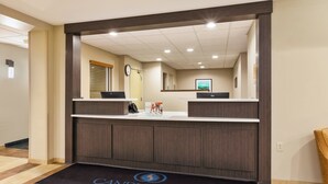 A reception area with a dark wood reception desk, a black doormat with "CANDLEWOOD SUITES" logo, and a clock on the wall. - Candlewood Suites Washington North by IHG (Washington)