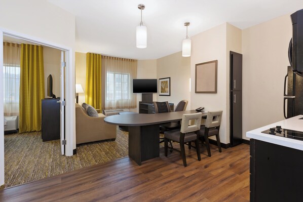 Een moderne hotelkamer met een zithoek, een flatscreen televisie, een sofa en een keukenhoek met een fornuis.