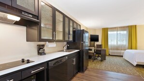 A compact hotel room with a kitchenette, a bed, a desk, and a television. - Candlewood Suites Washington North by IHG (Washington)