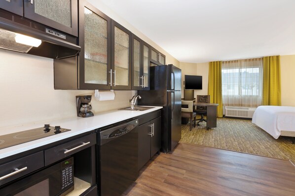 A compact hotel room with a kitchenette, a bed, a desk, and a television. - Candlewood Suites Washington North by IHG (Washington)