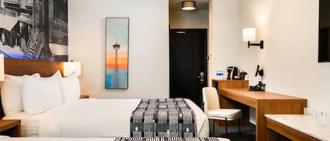 Habitación de hotel con cama, escritorio, silla, un cuadro de una torre y una puerta.