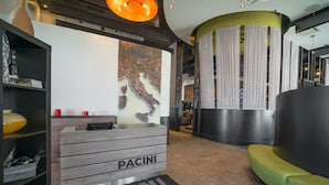 A reception area with a wooden desk labeled "PACINI," a green sofa, and a wall with a map.