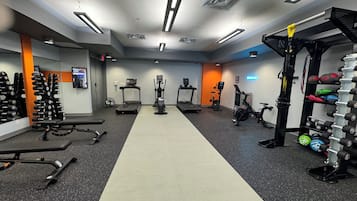 Un gimnasio con cintas de correr, elípticas y equipo de levantamiento de pesas.