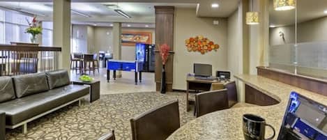 A hotel lobby with a seating area, a reception desk, and a counter.