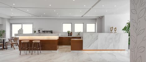 A modern kitchen with a marble countertop, wooden stools, and a central island.