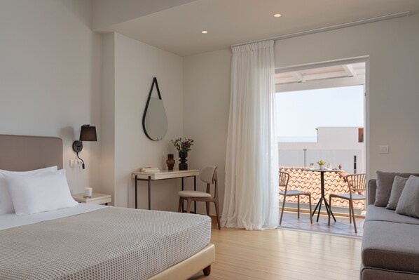 A hotel room with a bed, a desk, a chair, and a balcony with a table and chairs.