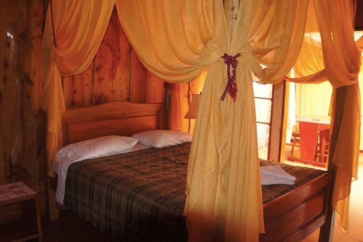 A wooden cabin-style room with a bed, a small table, and a chair.