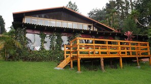 A rustic wooden house with a balcony, surrounded by lush greenery. - Hotel El Portico (San Jose De La Montana)